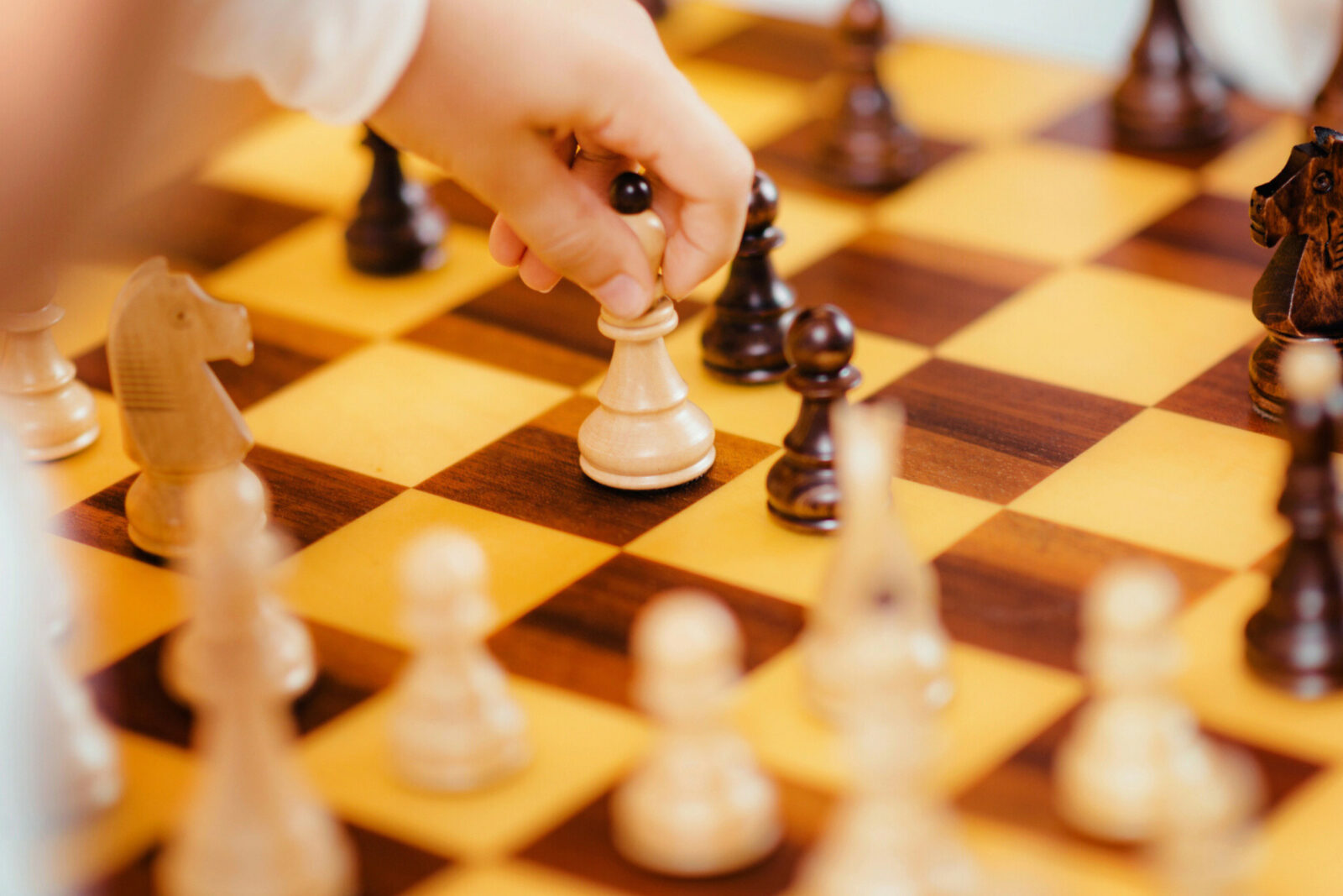 dreieins Innovative Pädagogik – dreieins Kreativitätsbereich Schach: Abgebildet ist ein Schachspiel und eine Kinderhand, die eine Schachfigur bewegt.
