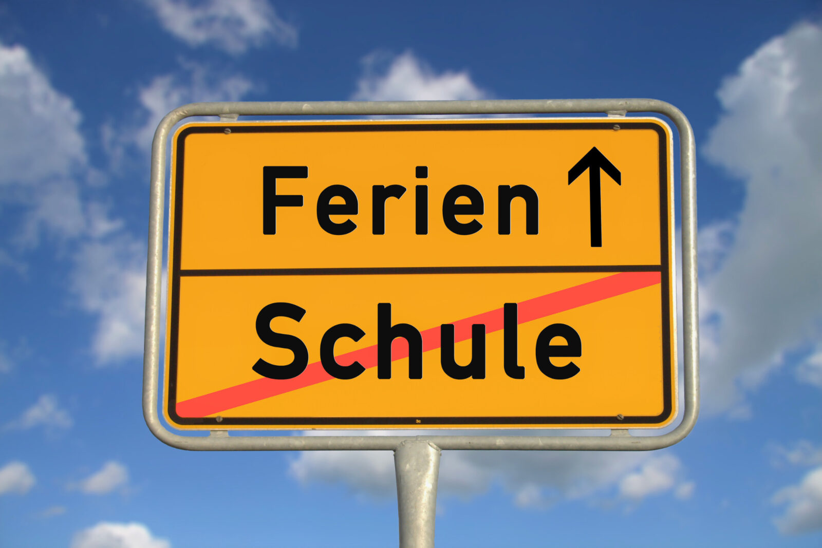 dreieins Grundschule Aachen - Endlich Ferien: Auf dem Bild ist ein Schild zu sehen, auf dem das Wort Schule durchgestrichen ist und das Wort Ferien mit einem Pfeil versehen ist.