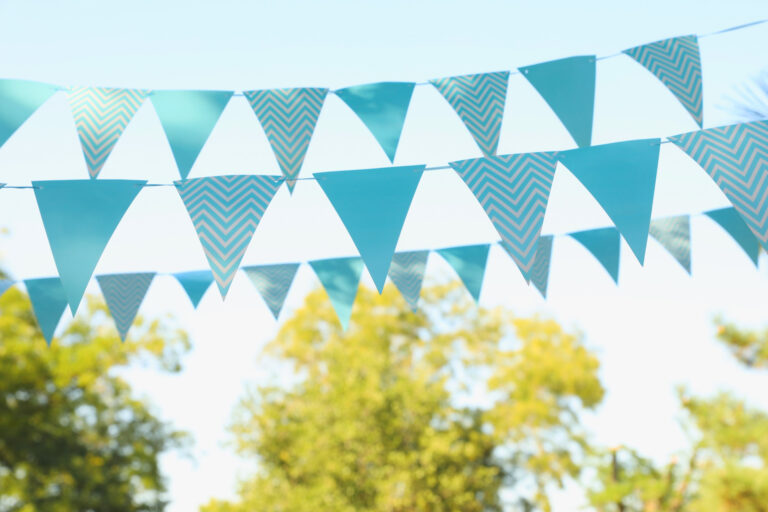 dreieins Kita Aachen - Sommerfest: Abgebildet sind blaue Wimpelketten im Vordergrund und Bäume im Hintergrund.