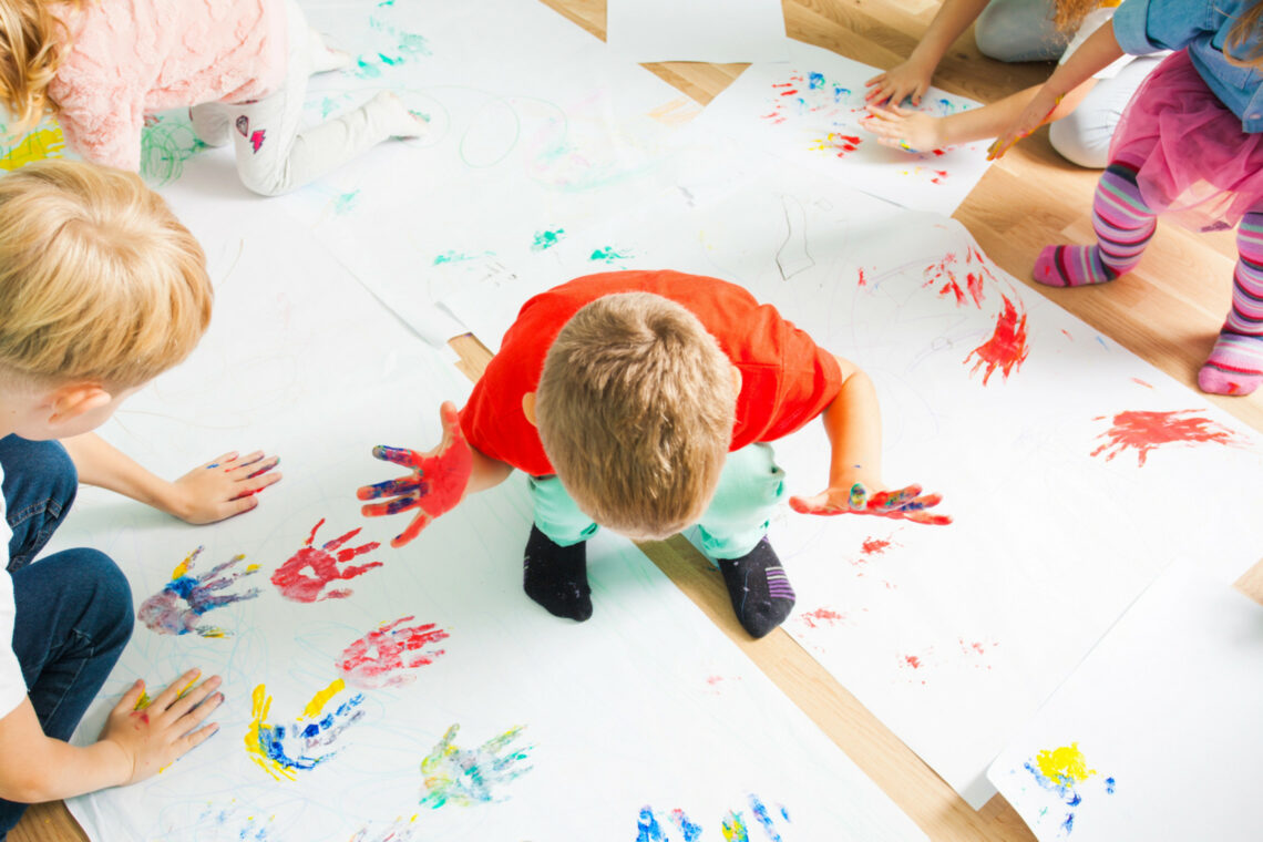 dreieins Innovative Pädagogik – dreieins Eingewöhnung: Abgebildet sind Kinder, die auf dem Boden auf Papier malen.