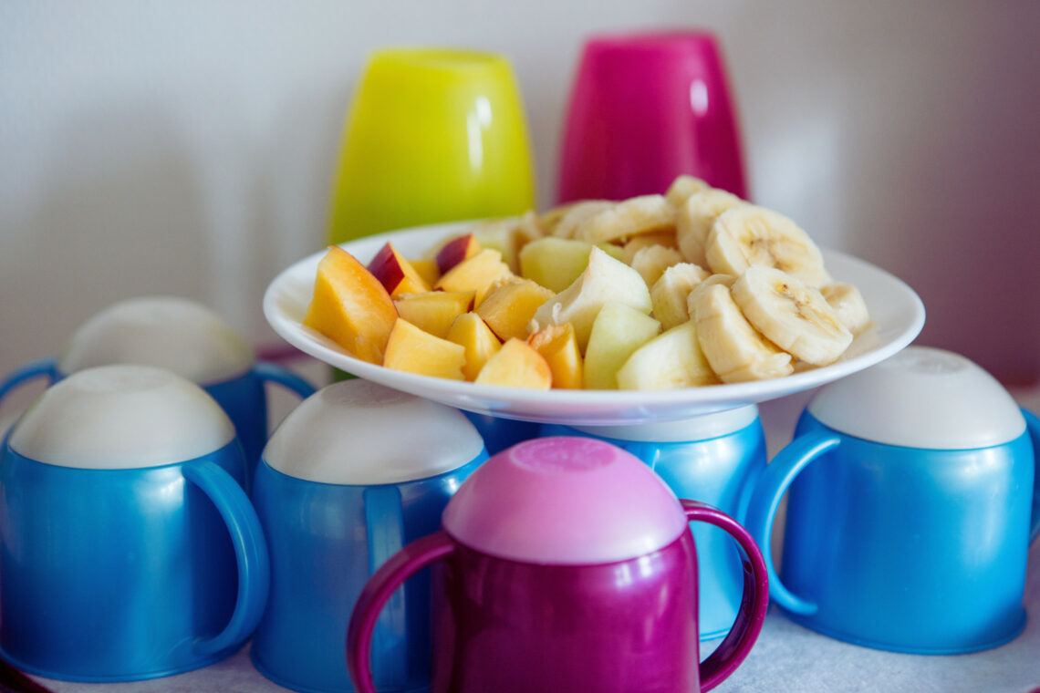 dreieins Innovative Pädagogik – dreieins Ernährung: Zu sehen, sind ein Obstteller sowie Becher und Tassen.