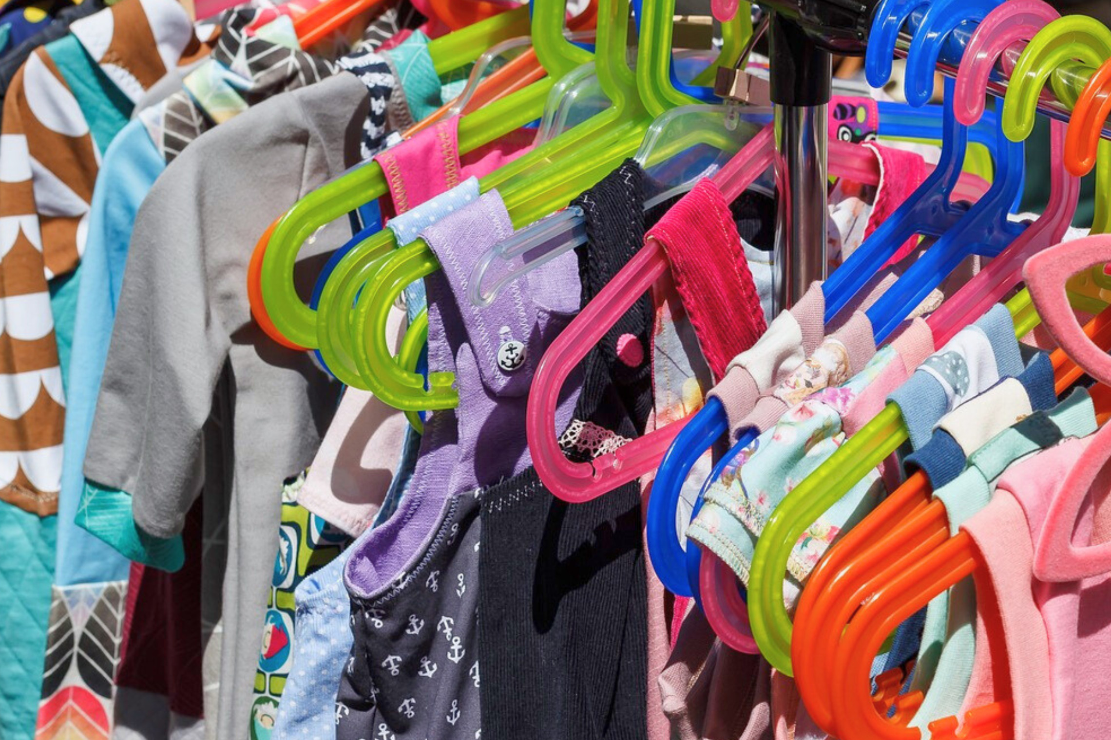 dreieins Kindertagesstätte Prenzlauer Berg - Flohmarktstand mit Kinderkleidung dreieins Kindertagesstätte Prenzlauer Berg - Flohmarktstand mit Kinderkleidung: Auf dem Bild zu sehen, sind verschiedene Kleidungsstücke auf Bügeln aufgehängt.