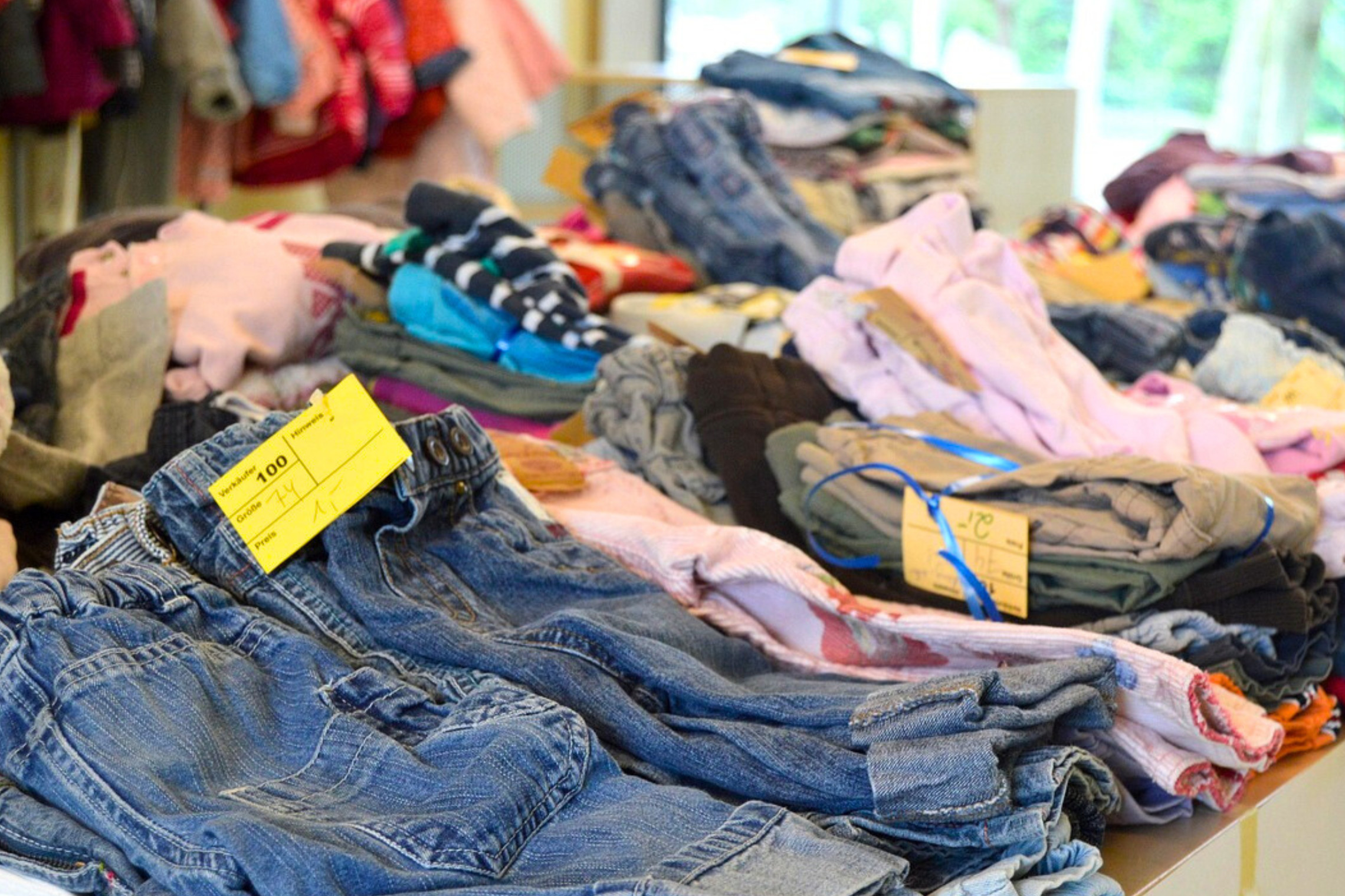 dreieins Kindertagesstätte Prenzlauer Berg - Kleidung für Kinder am Flohmarkstand dreieins Kindertagesstätte Prenzlauer Berg - Kleidung für Kinder am Flohmarkstand: Zu sehen auf dem Bild, ist sortierte Kleidung für Kinder an einem Flohmarkt-Stand.