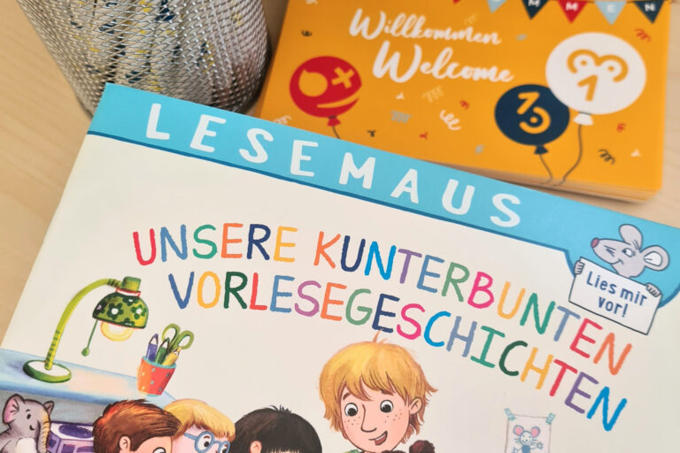 dreieins Kindertagesstätte Berlin - Berlin-Prenzlauer Berg - Landesprogramm Sprach-Kitas: Auf dem Bild sind Postkarten, ein kleines Buch und Bleistifte in einem Behälter zu sehen.